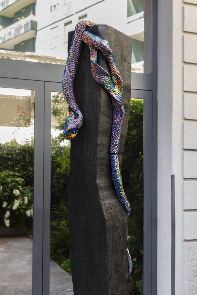 <i>Gloria</i>, 2022 </br>
burned wood and dichroic coating on glazed ceramic</br>
Gloria: 121,9 x 50,8 x 30,4 cm / 48 x 20 x 12 in</br>
trunk: 250 x 18 x 18 cm / 98.4 x 7 x 7 in