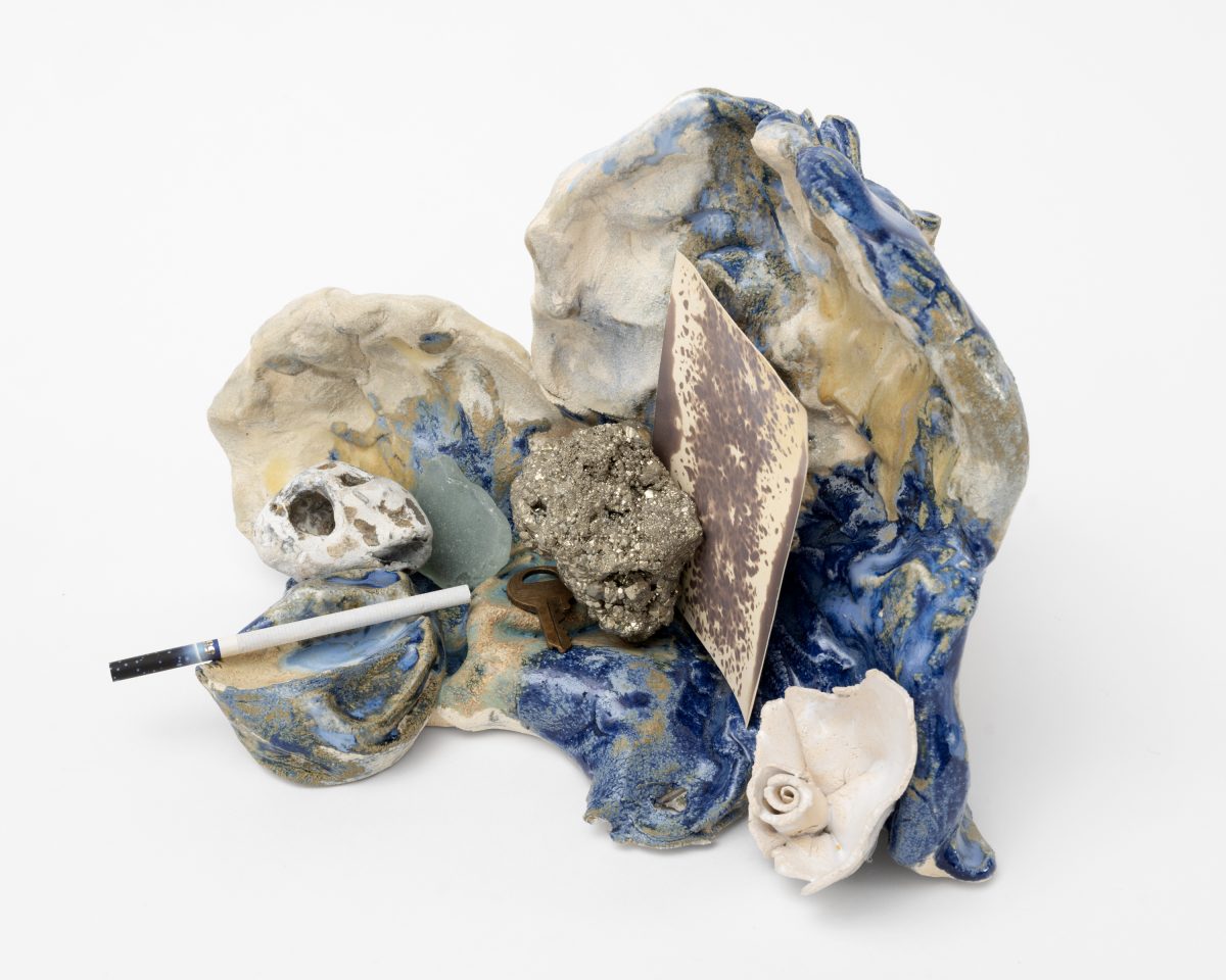 <i>Boudoir Salt,</i> 2025</br>
glazed ceramic, Chinese cigarette, pyrite, sea glass, stone, </br> film with the presence of salt, found key, white ceramic rose</br> 18 x 28 x 25,5 cm / 7.1 x 11 x 10 in