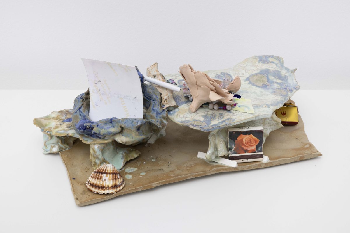 <i>Boudoir - Maybe close to the beach</i>, 2025</br>
glazed ceramic, film with the presence of salt, Chinese cigarette, shells, Chinese beads, a coin, a dice, matches, bubblegum paper, ceramic rose</br>15 x 43 x 22 cm / 5.9 x 16.9 x 8.6 in